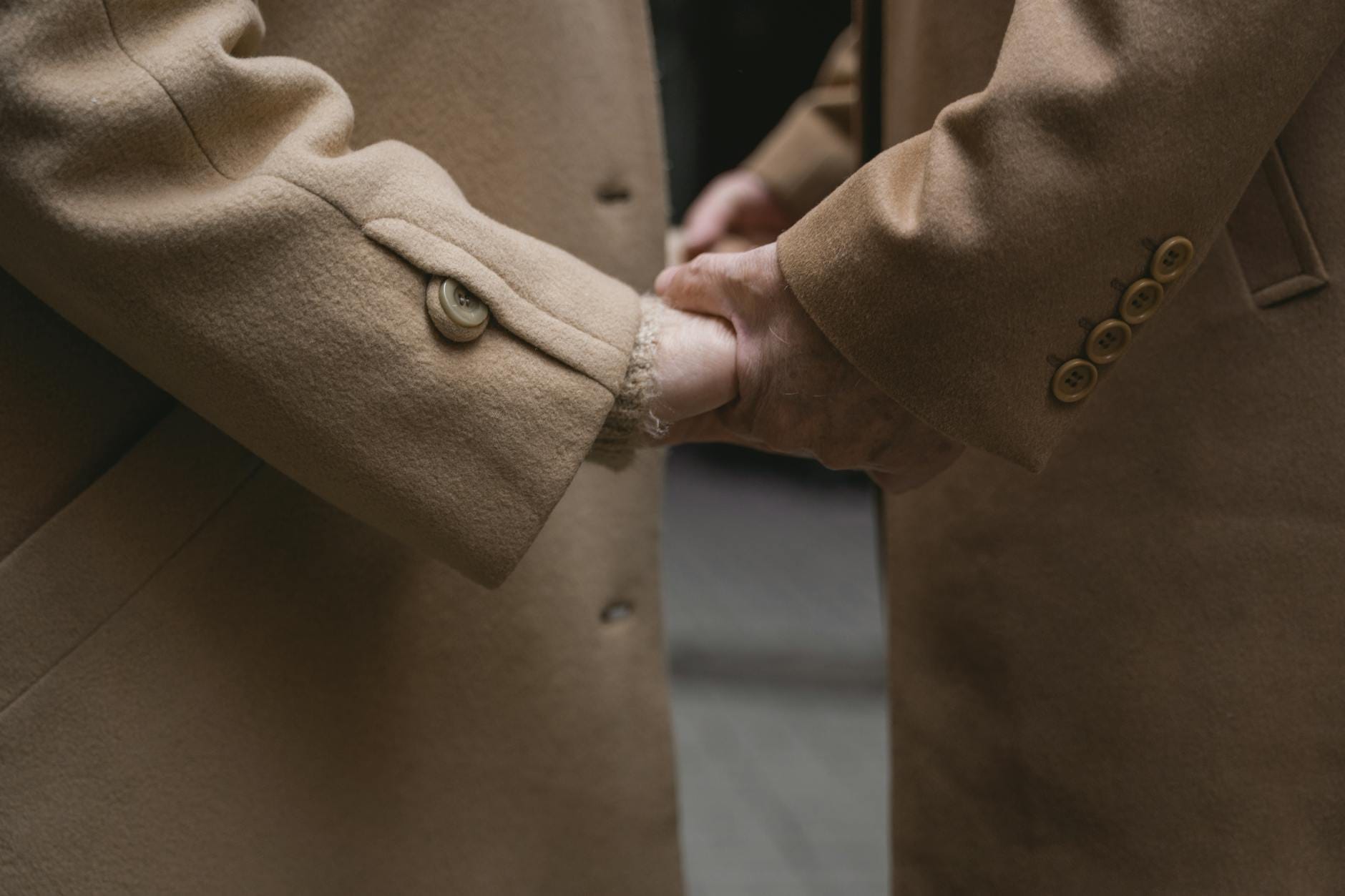Dwoje ludzi trzymających się za ręce w brązowych wełnianych płaszczach