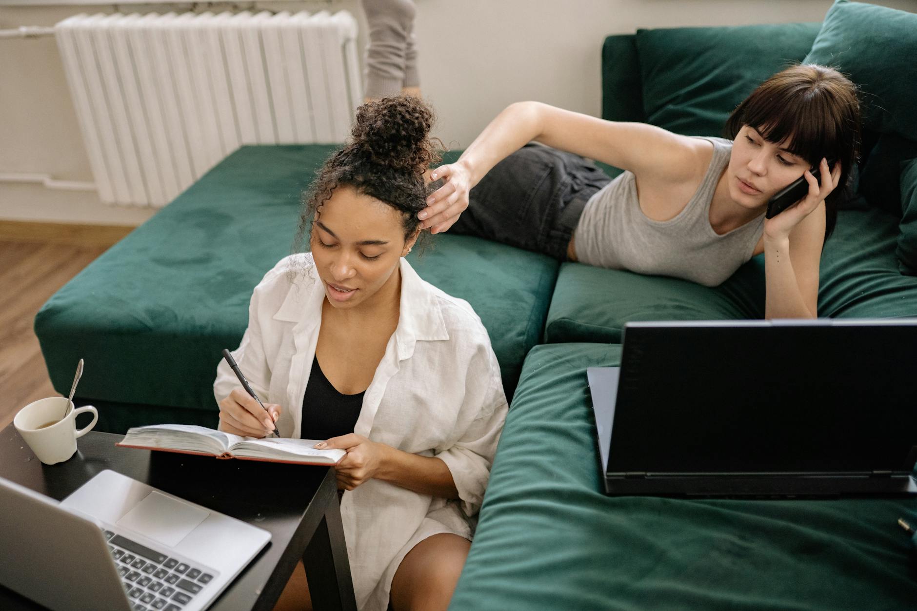 Lesbijska para na kanapie uczy się i pracuje na laptopach w przytulnym salonie