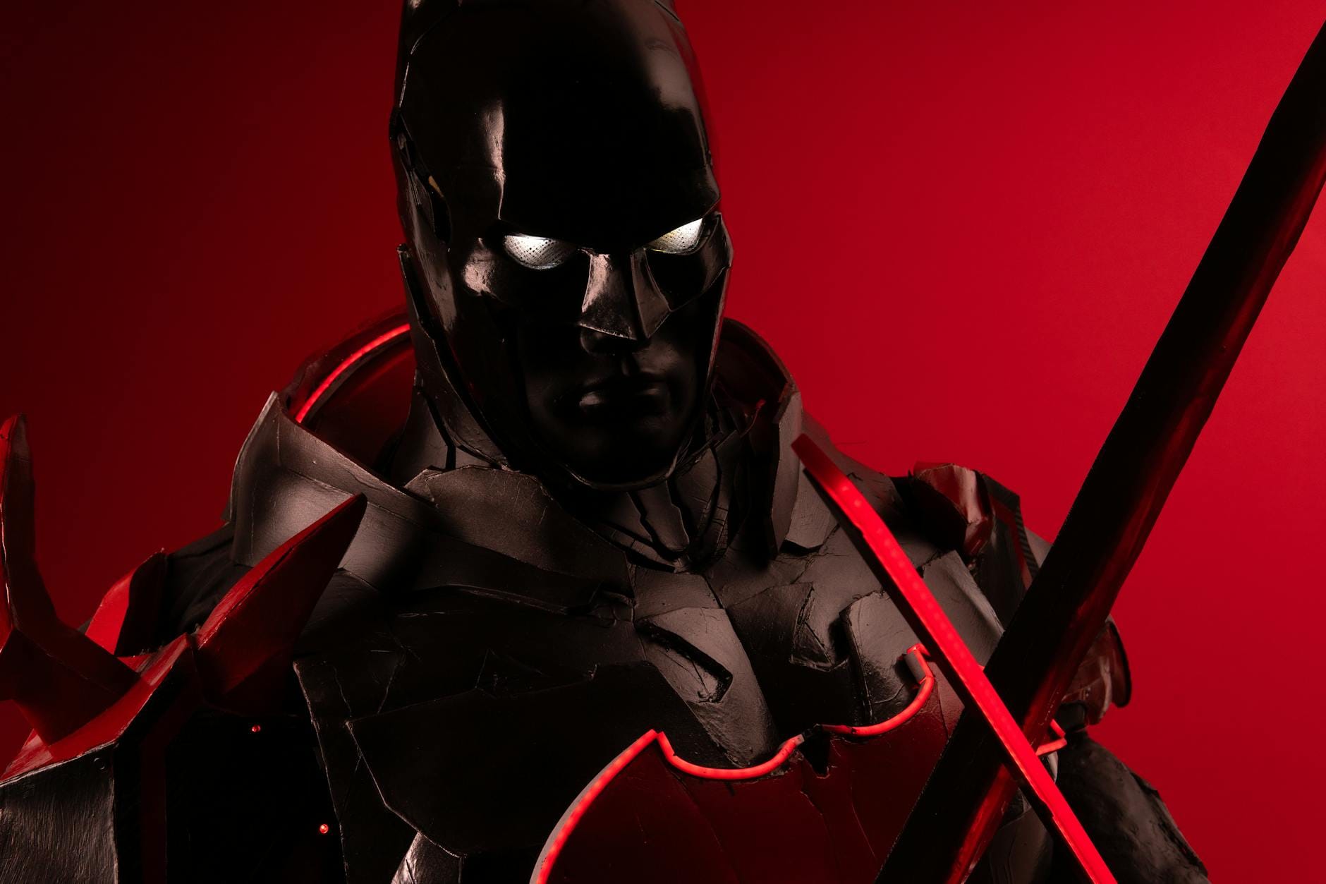 Cosplayer w czarno-czerwonej zbroi na tle intensywnej czerwieni