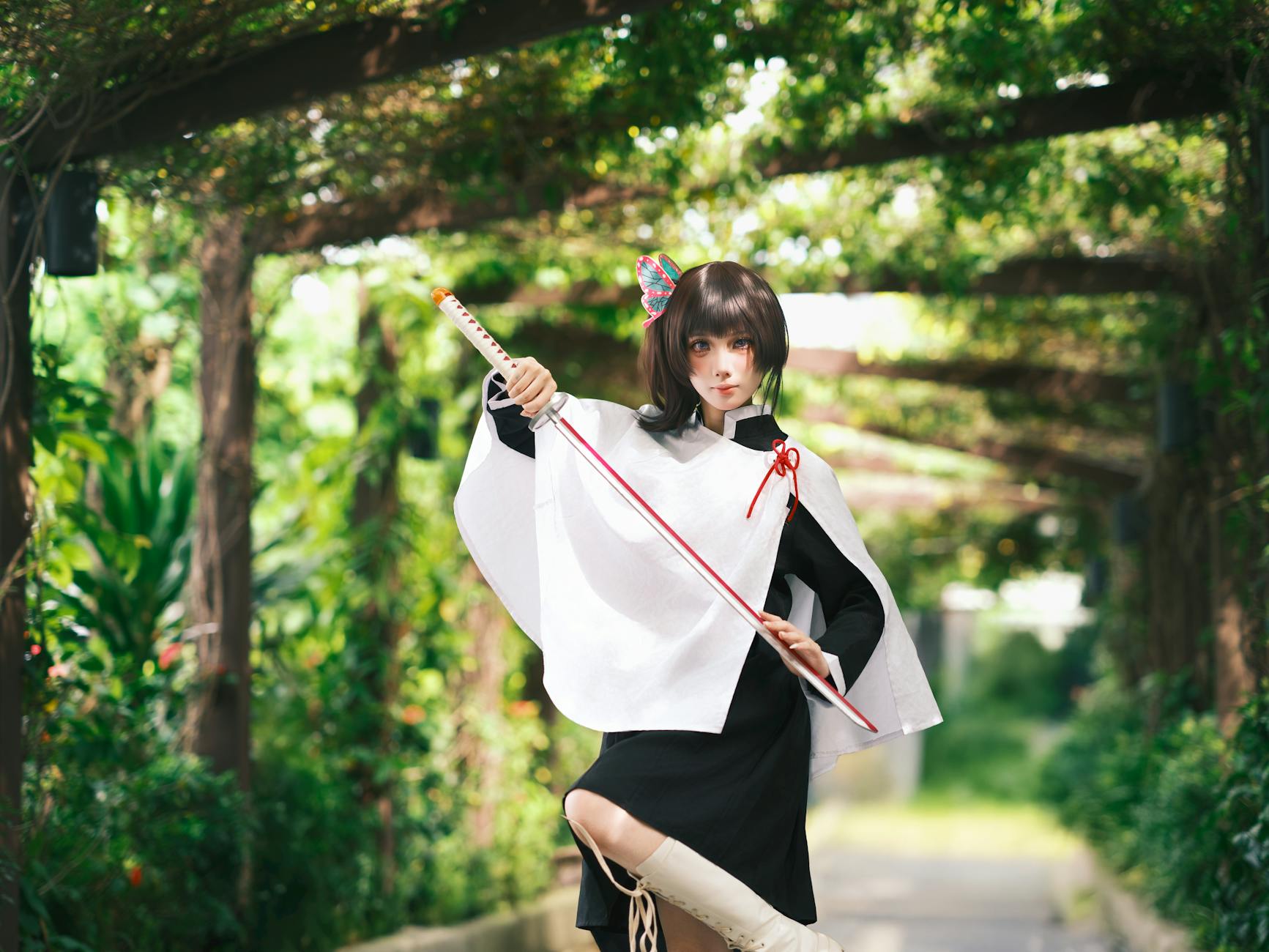 Jak zrobić pelerynę, która ładnie układa się na zdjęciach i nie spada Cosplayer z mieczem w pelerynie pozuje w zielonym plenerze