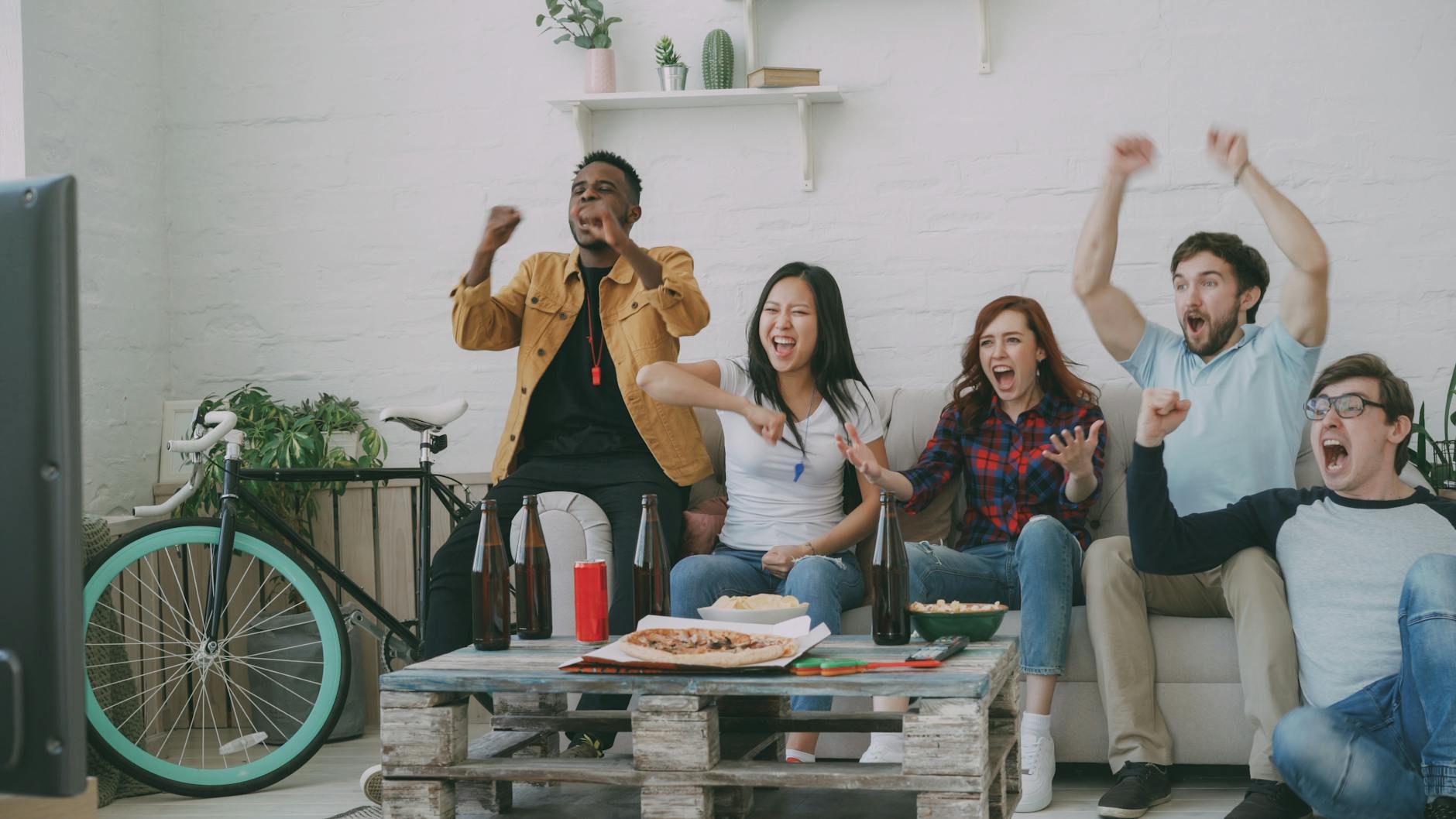 Grupa przyjaciół cieszy się ze zwycięstwa, oglądając coś razem w TV