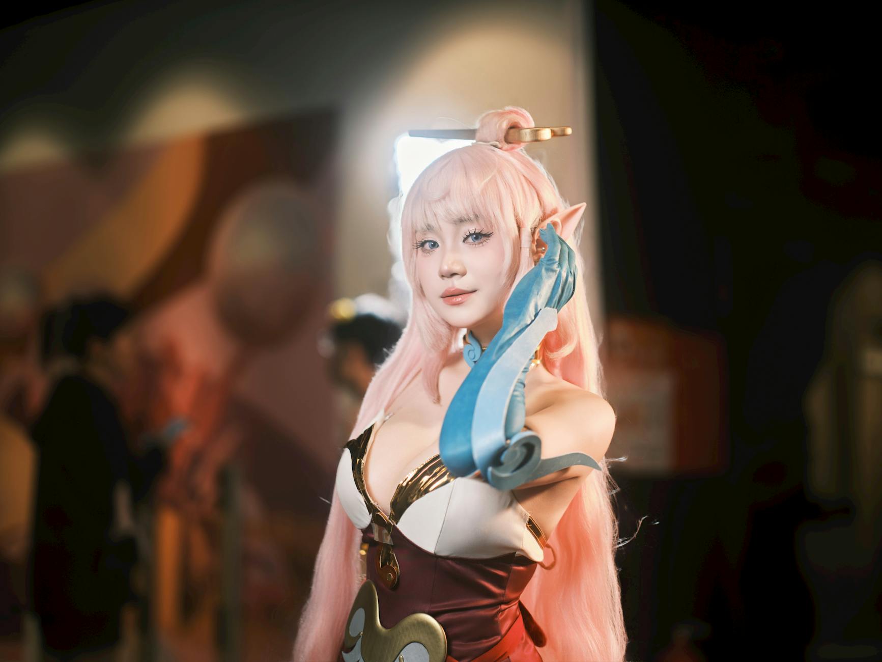 Cosplayer fantasy pozuje na konwencie w hali, kolorowe światła w tle