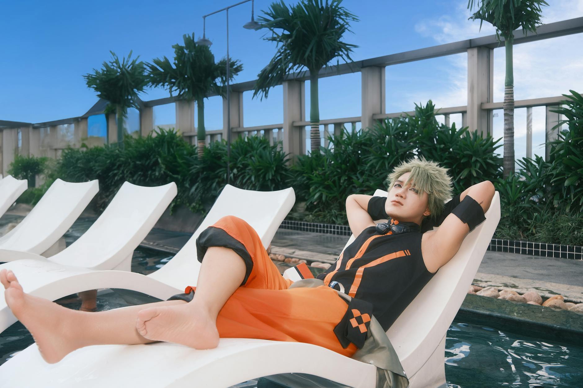 Cosplayer w kolorowym stroju odpoczywa na leżaku przy basenie