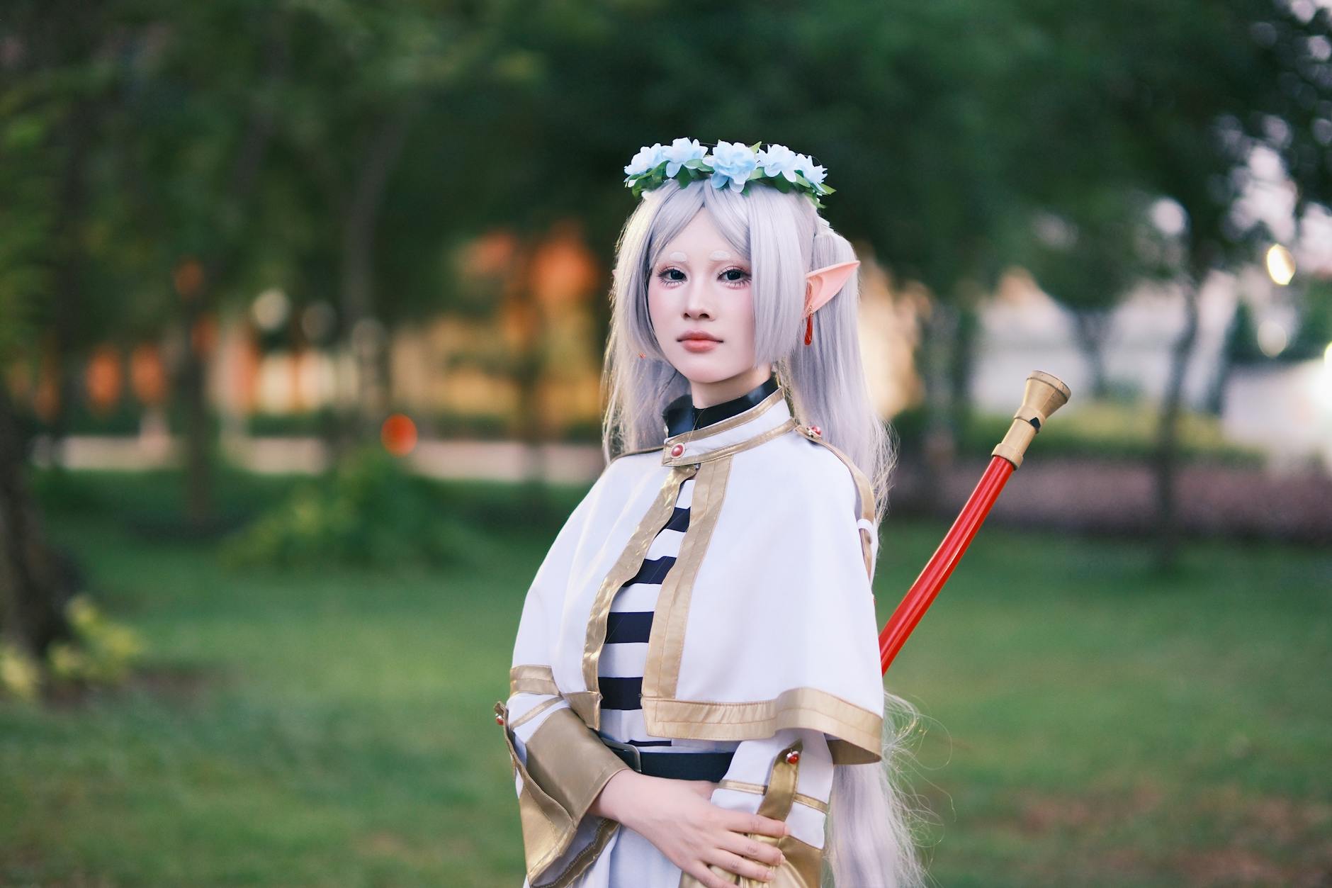Cosplayerka elfka o srebrnych włosach pozuje w parku