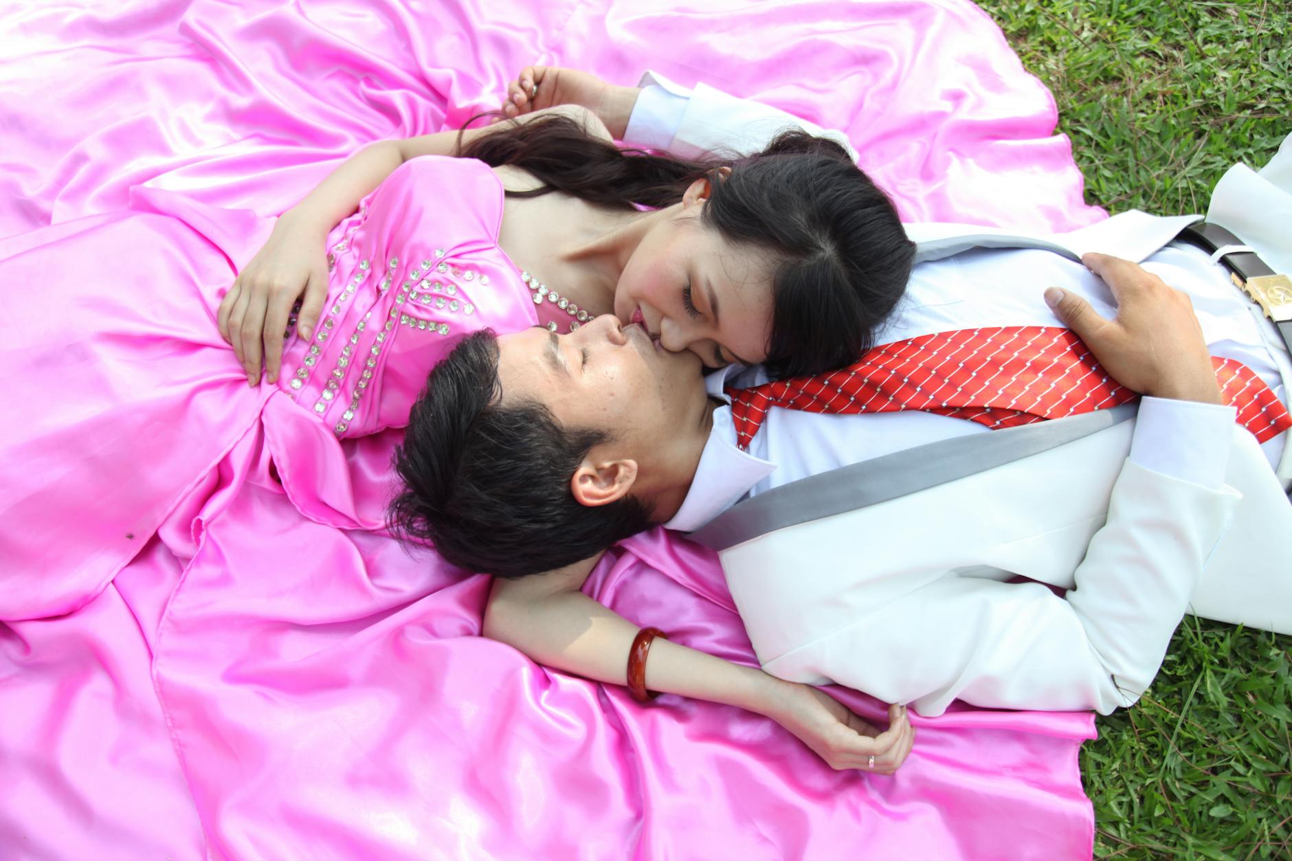 Elegancka para obejmuje się na różowym kocu na świeżym powietrzu