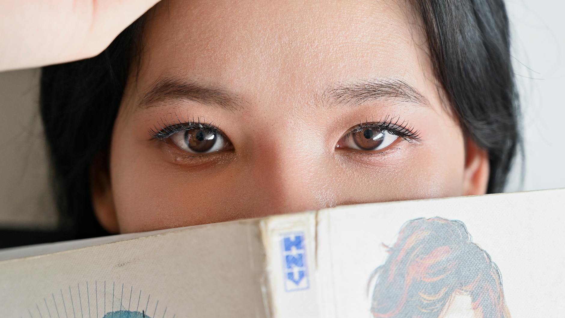 Oczy kobiety wyglądające znad czytanego komiksu manga