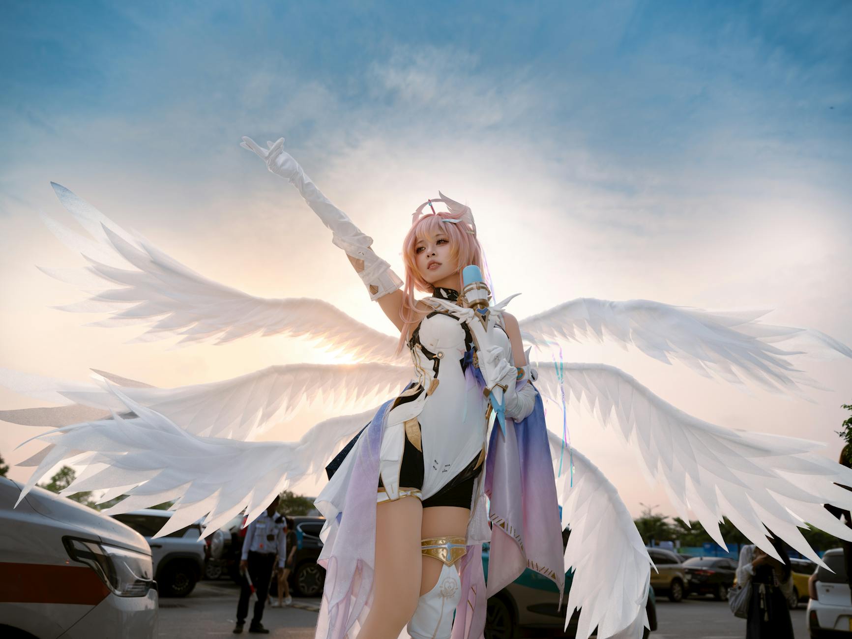 Cosplayerka z anielskimi skrzydłami na tle zachodzącego słońca
