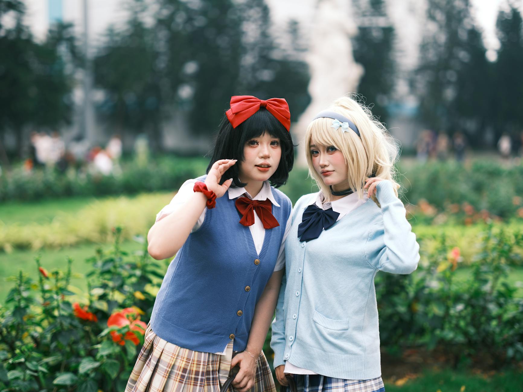 Dwie młode cosplayerki w szkolnych mundurkach w ogrodzie