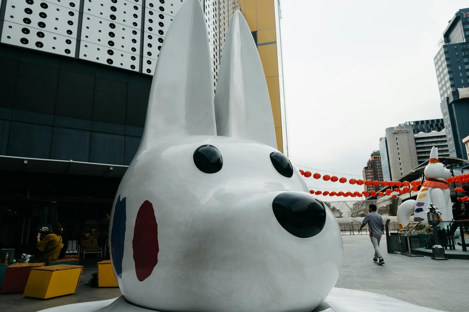 Figurka zabawnego królika przed nowoczesnym centrum handlowym