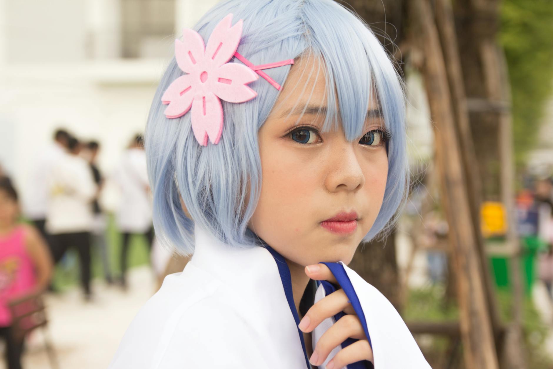 Młoda cosplayerka z niebieskimi włosami i kwiatową ozdobą na dworze