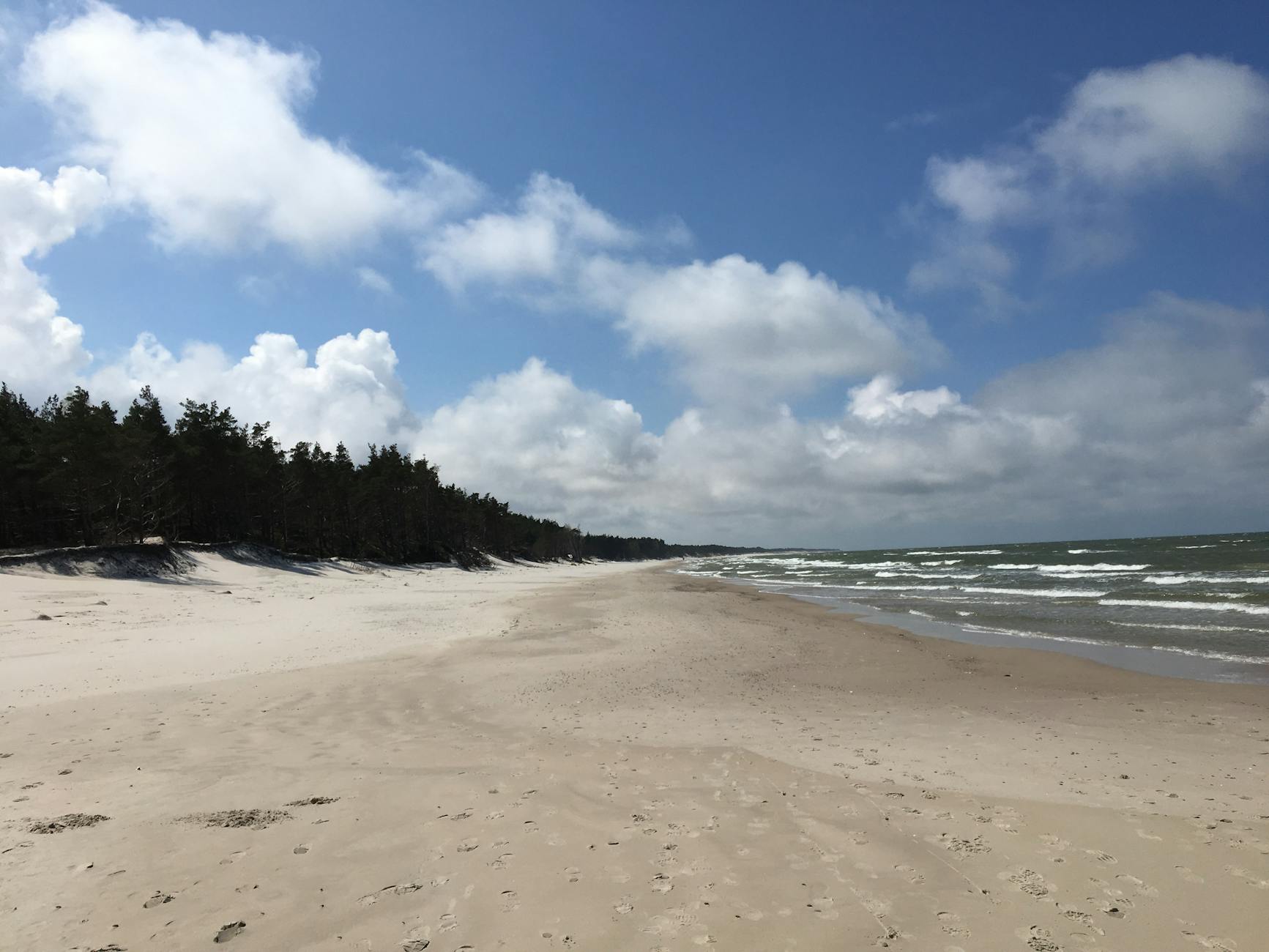 Spokojna plaża w Łebie z delikatnymi falami i błękitnym niebem