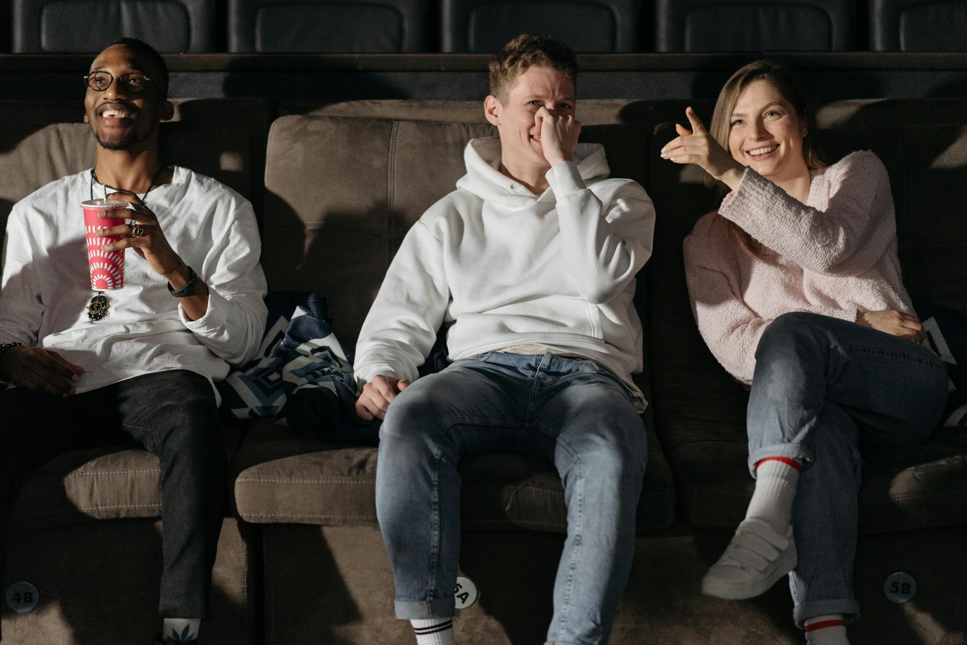 Troje przyjaciół śmieje się podczas seansu filmowego w przytulnym kinie