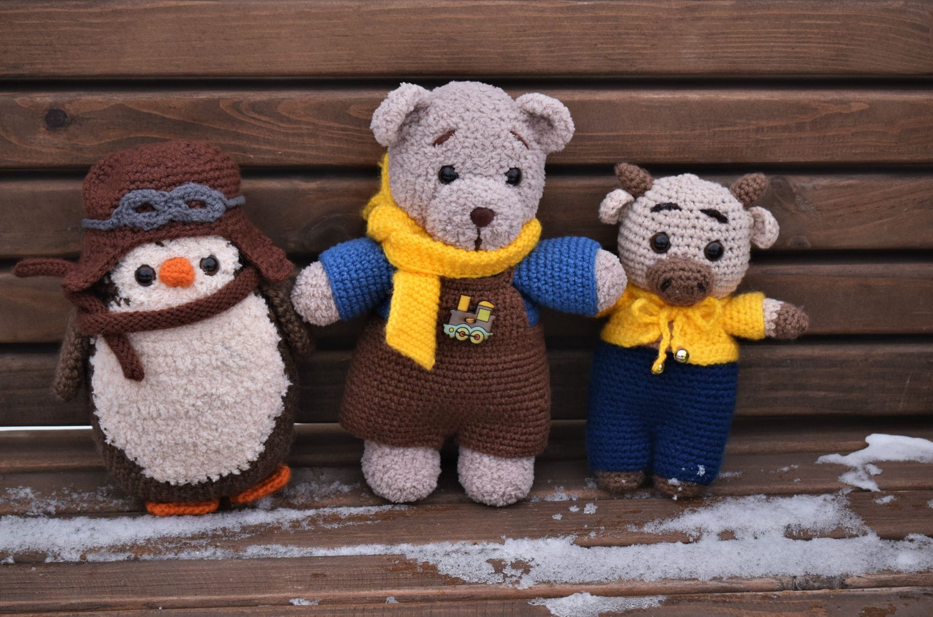 Pluszowe maskotki amigurumi na ośnieżonej drewnianej ławce