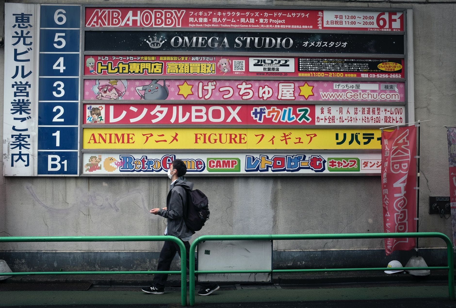 Mężczyzna idący obok kolorowych szyldów sklepów anime w Tokio