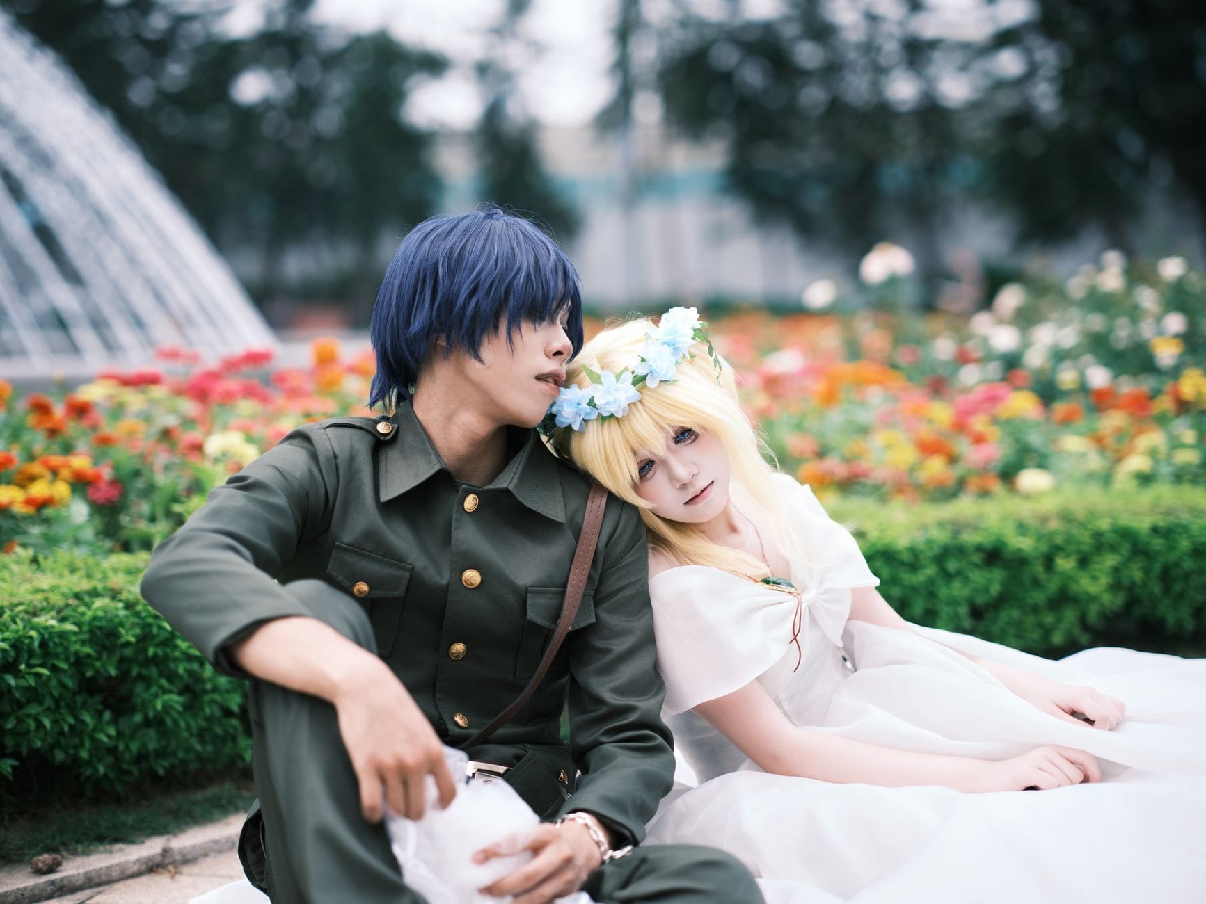 Para w cosplayu siedząca w kolorowym ogrodzie